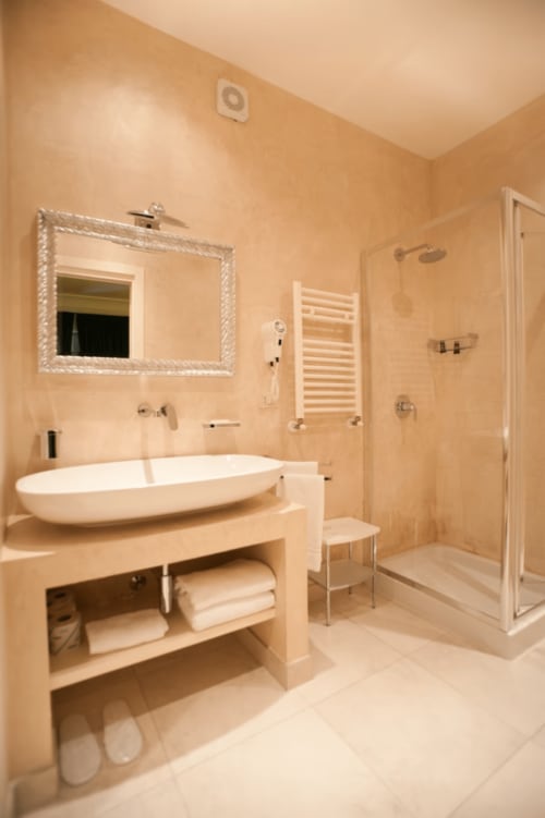 Modern bathroom at Al Mirador Resort with vessel sink, rainfall shower, heated towel rack, and marble finishes in Fasano.