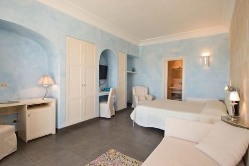 Spacious junior suite at Al Mirador Resort in Fasano with twin beds, light blue walls, white furnishings, and Jacuzzi tub
