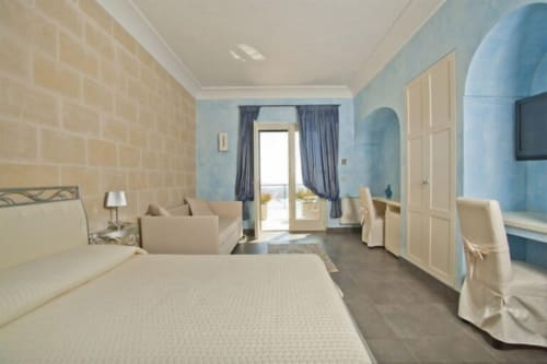 Spacious junior suite at Al Mirador Resort with bed, seating area, and terrace overlooking pool and sea