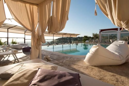 Luxuriöses Pooldeck im Al Mirador Resort in Fasano mit Sonnenliegen, cremefarbenen Baldachinen und türkisfarbenem Wasser