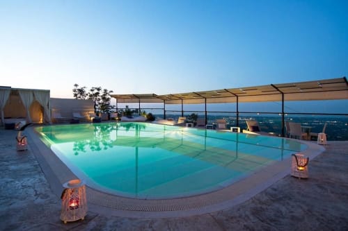 Dachpool des Al Mirador Resort in der Dämmerung mit türkisblauem Wasser, Meerblick und stimmungsvoller Laternenbeleuchtung in Fasano, Italien