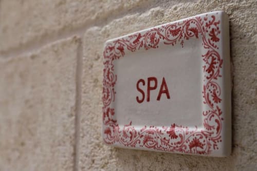 Decorative SPA sign with red ornamental border mounted on stone wall at Al Mirador Resort, Fasano