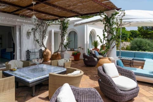 Terrazza lussuosa di La Conciergerie Capri con sedute in vimini, vista sulla piscina e architettura mediterranea