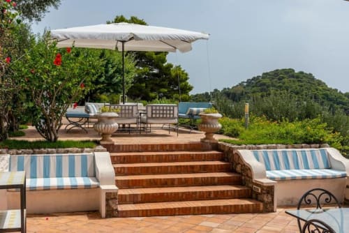 Terrazza La Conciergerie Capri con lettini a righe, ombrellone e vista sui monti di Capri
