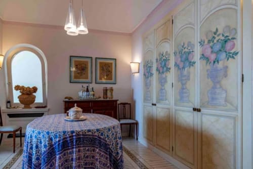 Elegante camera da letto a La Conciergerie Capri con tavolo rotondo, armadio decorato e pareti rosa