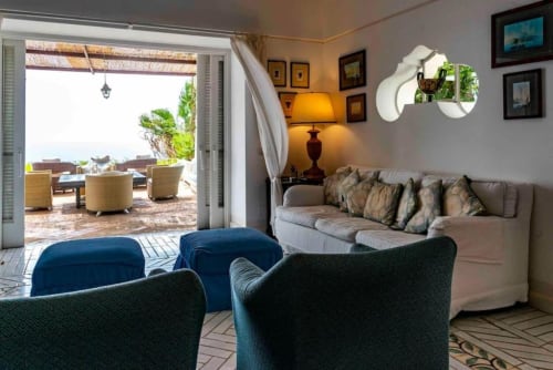 Lussuosa sala da soggiorno di La Conciergerie Capri con vista sul mare, poltrone blu e arredi eleganti