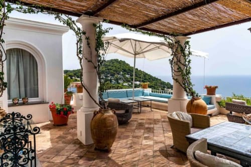 Terrazza di La Conciergerie Capri con vista mare, pergolato, zone lounge e giardini mediterranei affacciati sul Tirreno