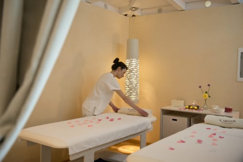 Spa therapist preparing massage bed with pink petals at Al Mirador Resort in Fasano