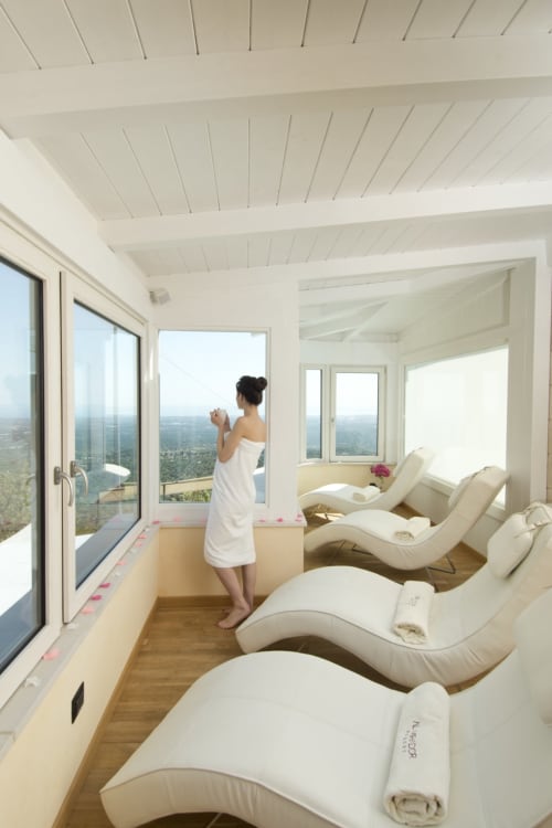 Woman in white towel at Al Mirador Resort spa overlooking Fasano landscape from lounge chairs