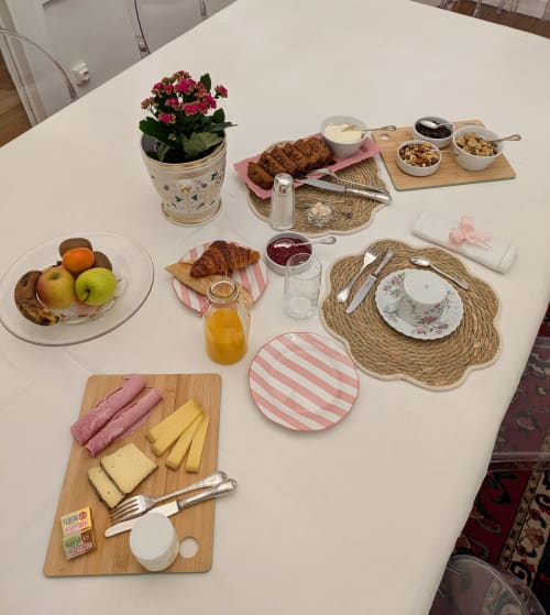 Elegant breakfast spread at Manoir Saint Joseph in Sens with croissants, fresh fruit, cheese, and pink striped tableware.