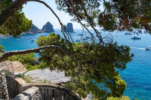Vista del mare turchese dalla villa La Conciergerie a Capri con gli scogli Faraglioni e barche ancorate