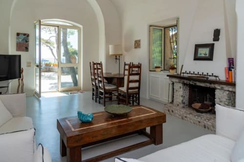Luminoso interno di villa mediterranea a La Conciergerie Capri con camino, arredamento in legno, porte con vista mare e design moderno