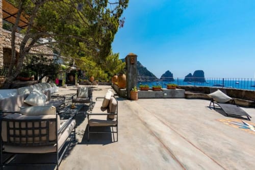 Terrazza soleggiata di Villa La Conciergerie Capri con vista mare, zone lounge e gli Faraglioni sullo sfondo
