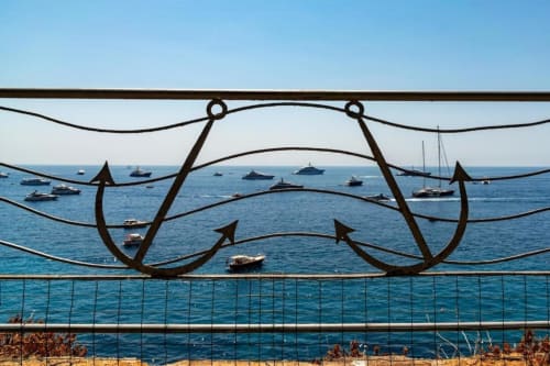 Balaustra decorativa con ancore che incornicia le acque turchesi di Capri e gli yacht ormeggiati dalla terrazza della villa