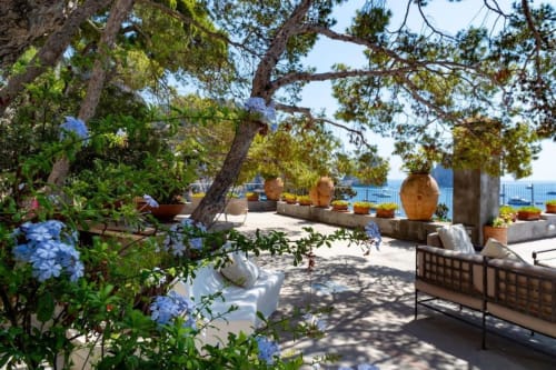 Terrazza di villa a Capri con ortensie blu, vista mare, ceramiche tradizionali e aree salotto ombreggiate presso La Conciergerie