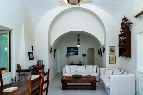 Soggiorno di una villa mediterranea a La Conciergerie Capri con archi bianchi, vista mare e arredi in legno