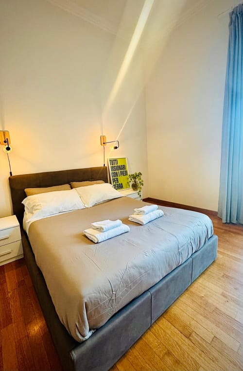 Camera da letto moderna in Todo Sicily Apartment a Catania con letto matrimoniale, biancheria bianca, pavimenti in legno e vista giardino