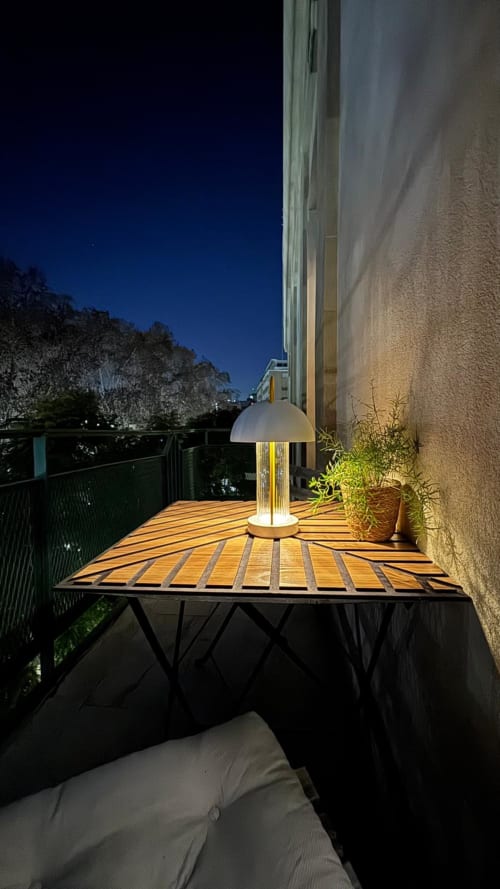 Balcone illuminato dell'appartamento Todo Sicily a Catania con terrazza in legno, lampada moderna, piante in vaso e viste montane
