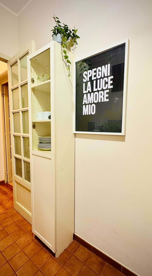 Area cucina moderna nel B&B di Catania con mobile in vetro bianco, stoviglie, pianta sospesa e arte murale d'ispirazione italiana