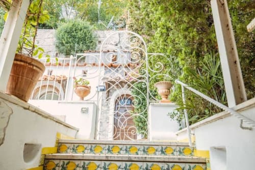 Scalinata con piastrelle al limone di Villa La Conciergerie Capri che conduce a cancellata ornamentale e vista sul giardino rigoglioso