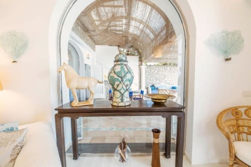 Elegante consolle nella villa La Conciergerie di Capri con statuetta decorativa di cavallo e vaso ornamentale affacciato