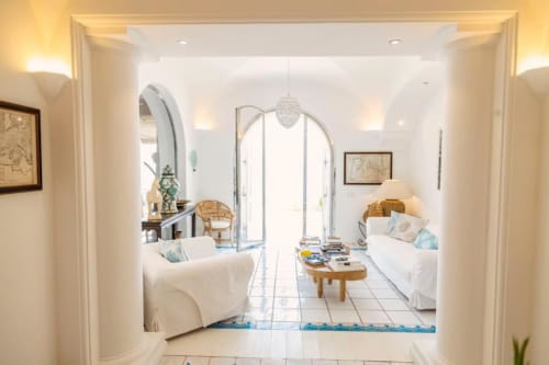 Suite luminosa di La Conciergerie Capri con letti gemelli, porta ad arco e vista mare dalle porte vetrate