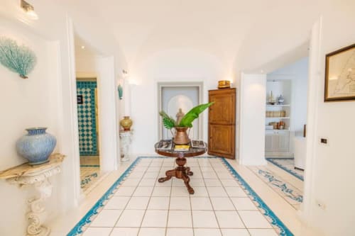Elegante corridoio della villa La Conciergerie Capri con pavimenti in maiolica blu, arredi classici e accesso alla vista sul mare
