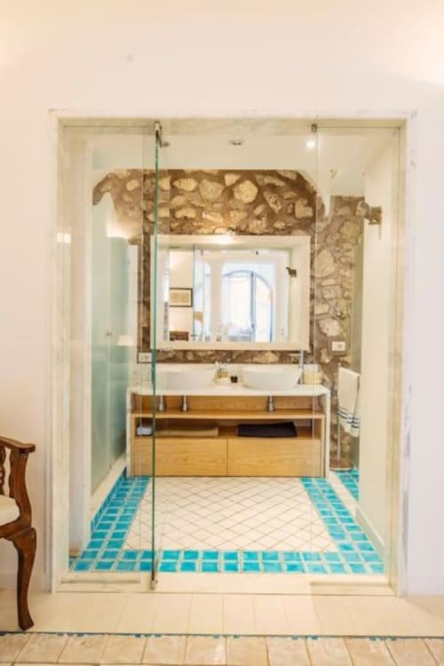 Bagno moderno con accenti di piastrelle turchesi, mobile in legno e specchio incorniciato a Villa La Conciergerie Capri