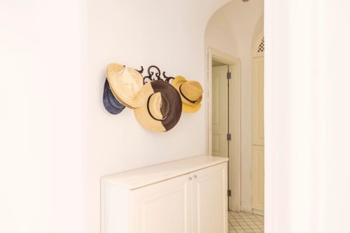 Ingresso villa di Capri con appendiabiti decorativo con cappelli di paglia e marrone sopra mobile color crema