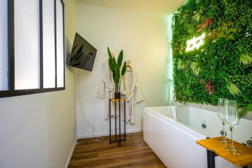 Modern bathroom with soaking tub, green living wall, flat-screen TV, and wood flooring at Wellkhome Bordeaux