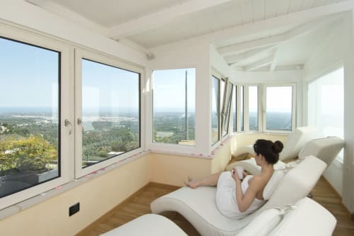 Woman relaxing on lounge chairs in bright sunlit room overlooking landscape at Al Mirador Resort, Fasano