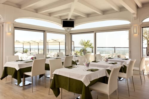 Al Mirador Resort's elegant dining room with panoramic valley views, white ceiling beams, and olive-toned tablecloths in