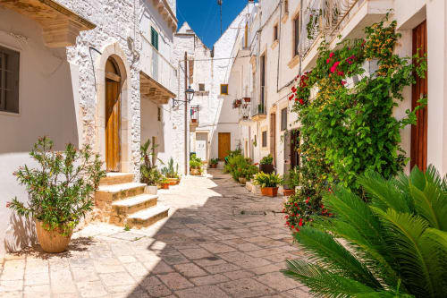 Charming whitewashed alley at Al Mirador Resort in Fasano, Italy with flowering vines and traditional architecture
