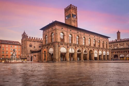 Piazza Maggiore a Bologna al tramonto con il Palazzo d'Accursio e l'architettura rinascimentale