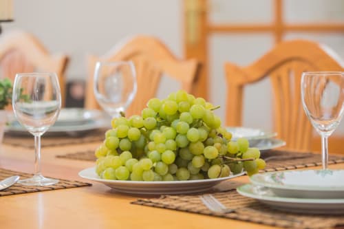 Elegant dining table with green grapes, wine glasses, and place settings at Finca de La Geria cottage in Yaiza