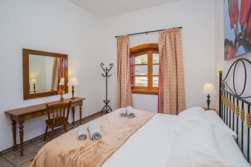 Spacious bedroom at Finca de La Geria cottage with twin beds, wooden furniture, garden views, and traditional décor