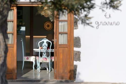 Wooden cottage entrance at Finca de La Geria with turquoise chair visible inside, garden view, Yaiza