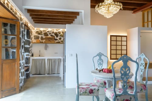 El Granero cottage interior at Finca de La Geria with blue vintage chairs, floral upholstery, exposed beams, and rustic stone