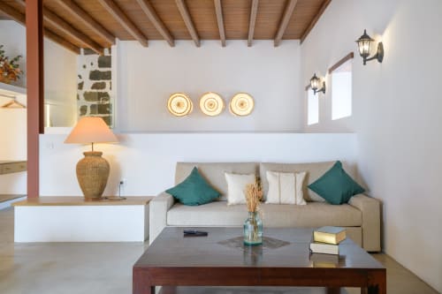 Bright living room in El Granero cottage at Finca de La Geria with beige sofa, teal pillows, wooden beams, and garden views
