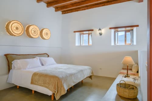 Bright bedroom at El Granero cottage in Finca de La Geria with queen bed, woven basket wall décor, wooden beams, and garden