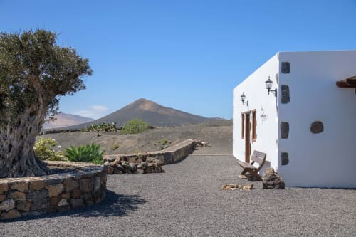 White cottage at Finca de La Geria in Yaiza with volcanic mountain views, grapevine landscape, and traditional architecture