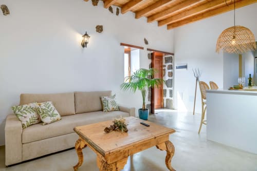 Bright living room at Finca de La Geria cottage in Yaiza with beige sofa, wooden table, and garden views