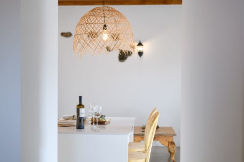 Modern dining area at Finca de La Geria cottage with wine bottle, glasses, and woven pendant light above table