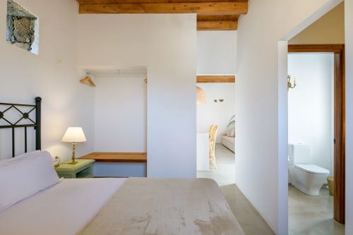 Bright bedroom at Finca de La Geria cottage in Yaiza with double bed, ensuite bathroom, wooden beams, and garden views