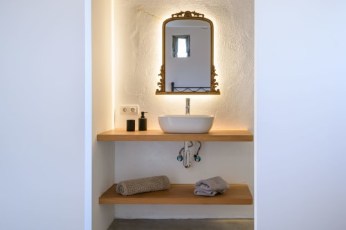 Modern bathroom vanity at Finca de La Geria cottage in Yaiza with vessel sink, brass mirror, and wooden shelving with towels