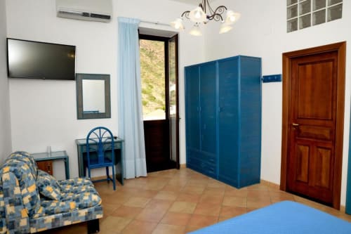Camera tripla dell'Hotel Principe di Rinella a Rinella con guardaroba blu, divano, scrivania e vista montagna