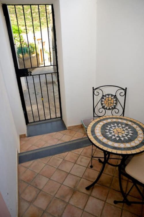 Area patio dell'Hotel Principe di Rinella con tavolo in mosaico e sedia in ferro battuto con vista montagna a Rinella