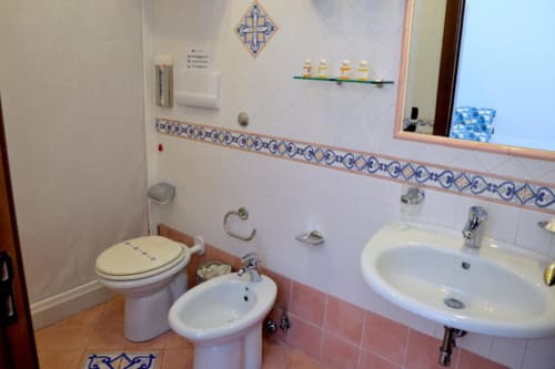 Bagno dell'Hotel Principe di Rinella con doppi lavabi, wc, bidet e piastrelle blu decorative a Rinella, Italia