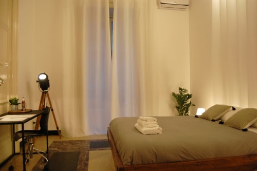 Camera moderna al Todo Sicily Apartment di Catania con letto queen, scrivania, lampada con treppiede e vista città dal balcone