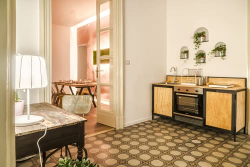 Angolo cottura moderno nella camera Aria dell'Aria Room a Todo Sicily Apartment a Catania con mobili in legno, piante sospese e pavimento geometrico